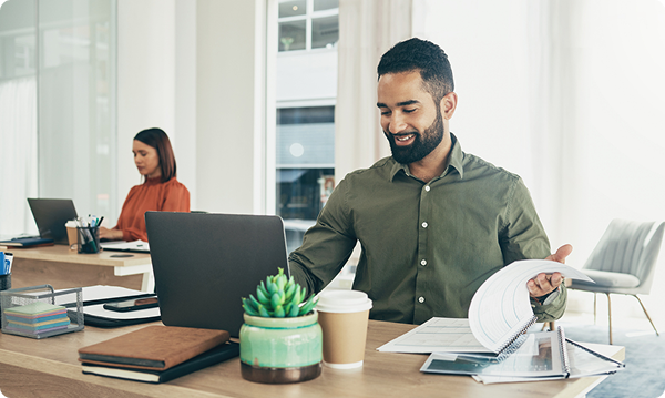 A man working on his laptop, a women in the background working on her laptop