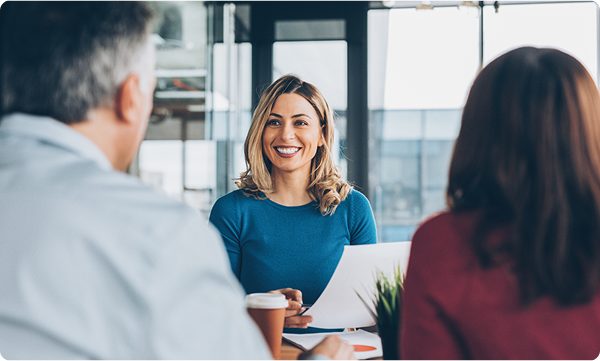 A woman sits at her desk meeting with two clients