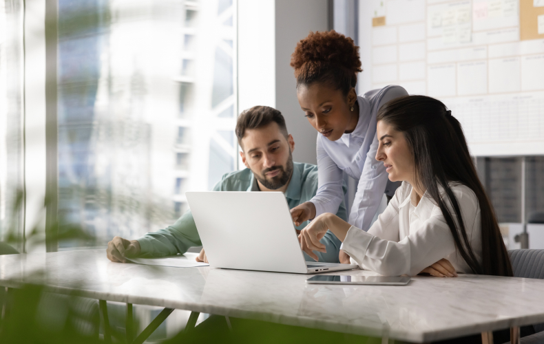 Three people huddled around a laptop.