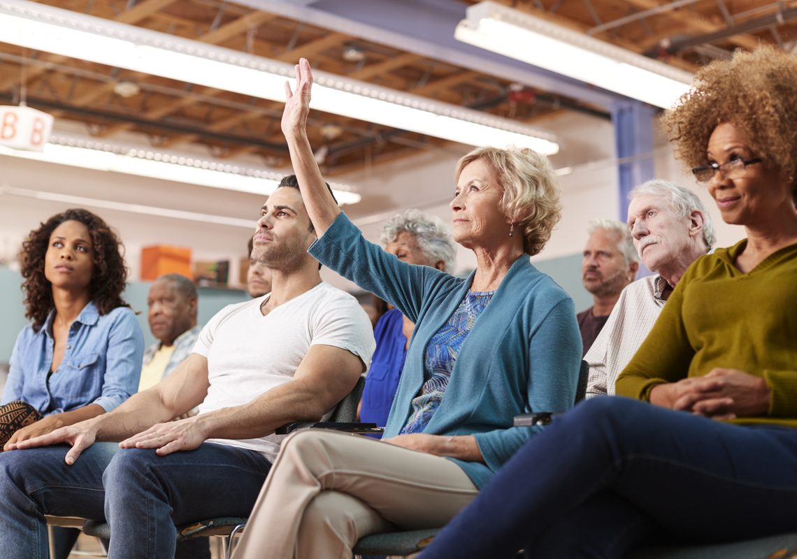 Homeowner raising a hand at an HOA community meeting